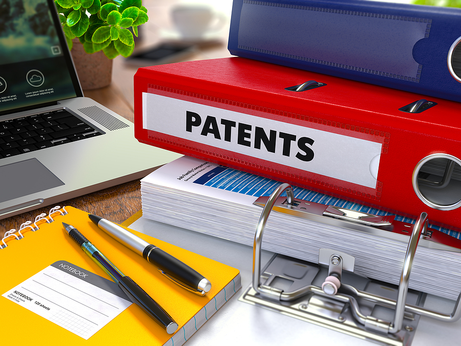 Patents and copyrights - Red Ring Binder with Inscription Patents on Background of Working Table with Office Supplies